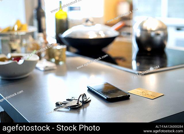 Close-up of smartphone, keys and credit card on kitchen worktop