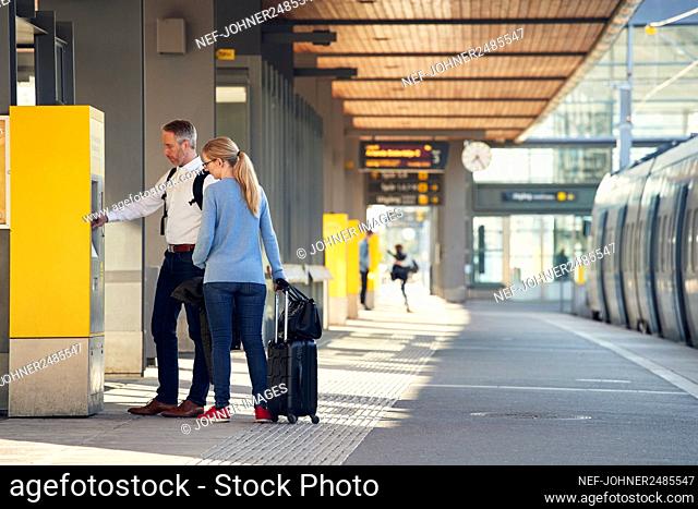 Couple using ticket machine at train station
