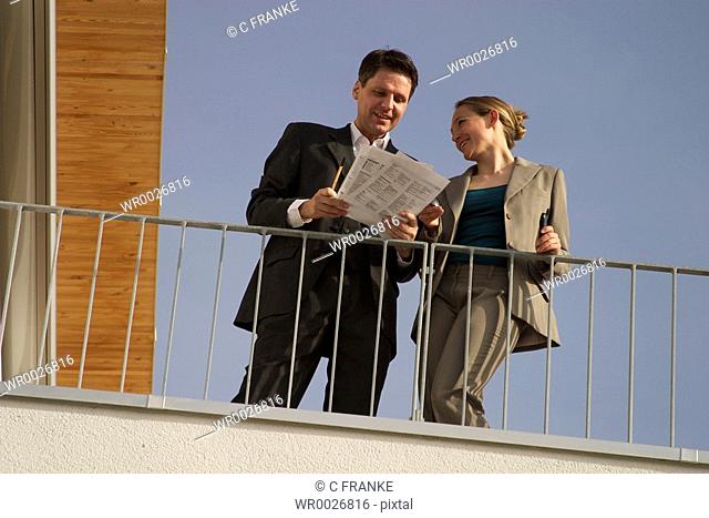 Low angle view of two businesspeople looking at documents on terrace