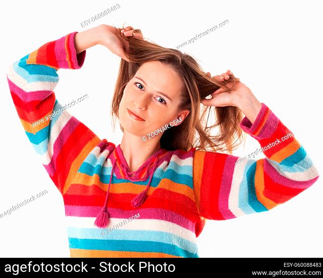 Young happy woman standing in colorfiul sweater and smiling grabs her hair