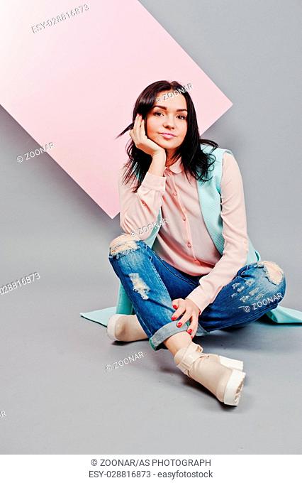 Full length studio portrait of young girl model at ripped jeans and rose blouse with pink banner board