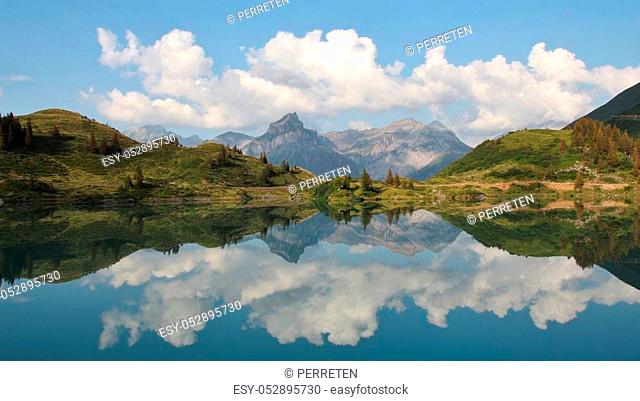 Summer clouds and mountains mirroring in lake Trubsee, Engelberg. Landscape halfway up on mount Titlis, Switzerland