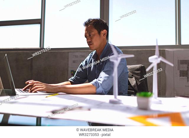 Male architect working on laptop at desk in a modern office