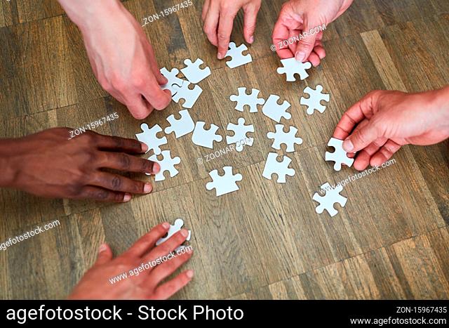 Leute spielen zusammen ein Puzzle als Gedächtnistraining gegen Demenz