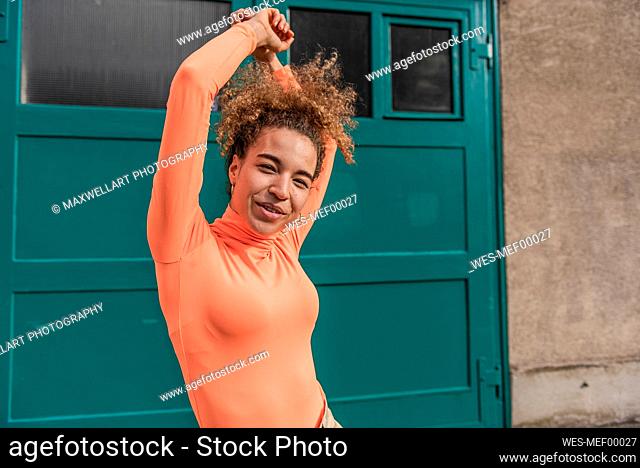 Young woman smiling while dancing against door