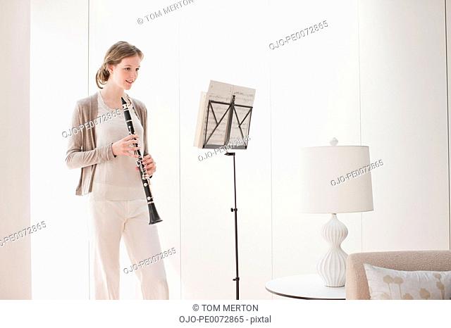 Woman holding clarinet and looking at sheet music
