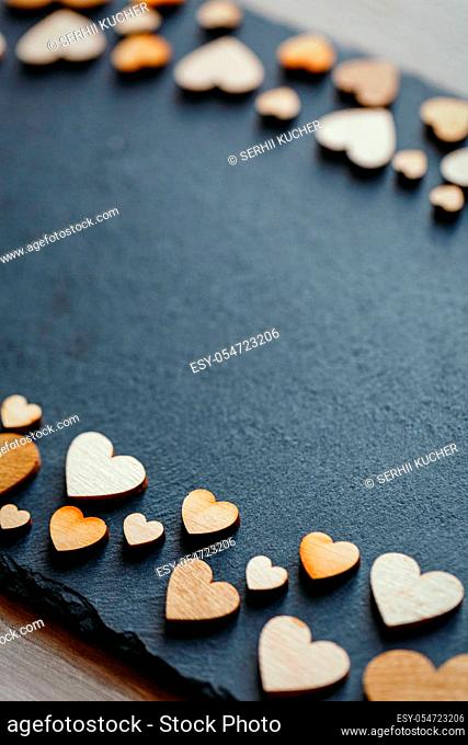 Heart shape made of natural wood. Beautiful heart shaped wooden little hearts on black background. Place for text