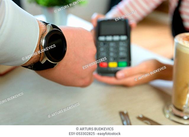 Customer making wireless or contactless payment using smartwatch. Store worker accepting payment with nfc technology
