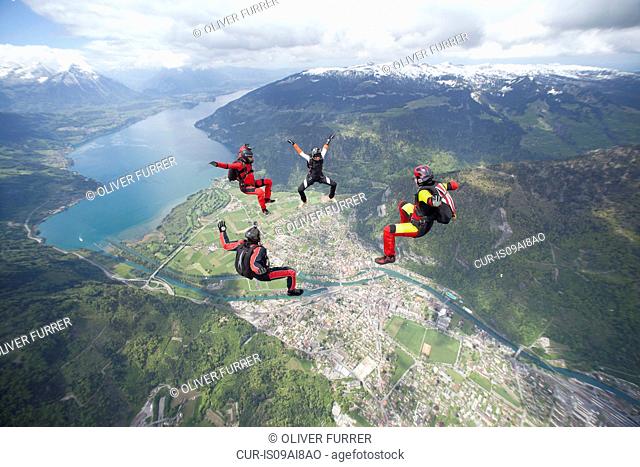 Team of four skydivers in formation over Interlaken, Berne, Switzerland