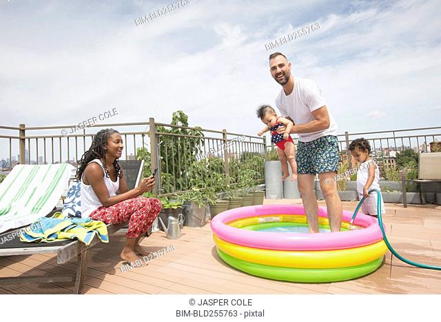 Padres jugando con niños en piscina inflable