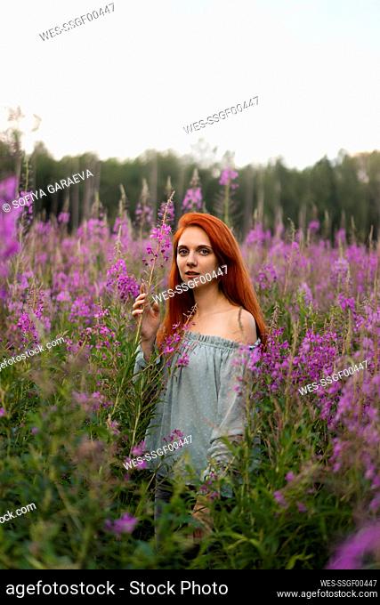 Redhead woman amidst pink flowers in field