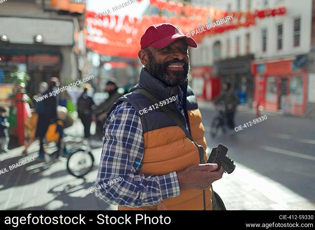 Happy male tourist with digital camera on city street