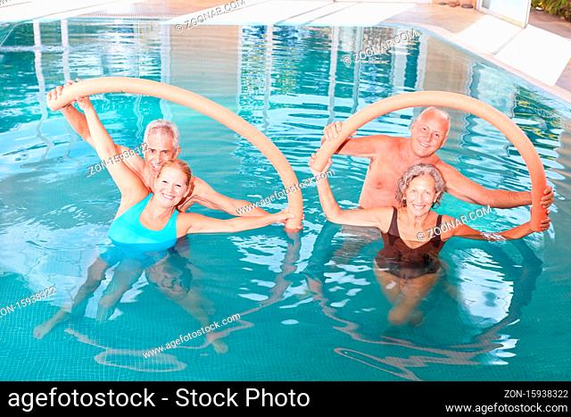 Senioren Gruppe macht Aquafitness als Rückentraining mit Schwimmnudel im Schwimmbad