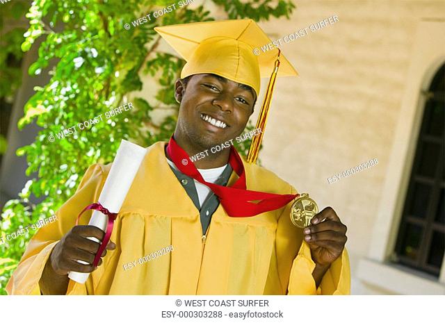 Graduate holding diploma and medal outside portrait