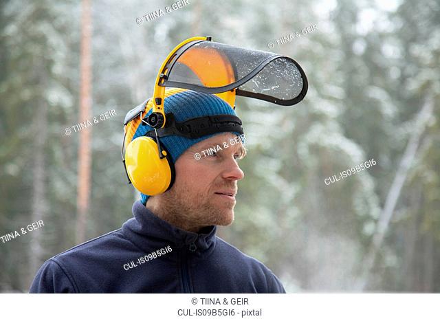 Logger wearing safety visor in forest, Tammela, Forssa, Finland