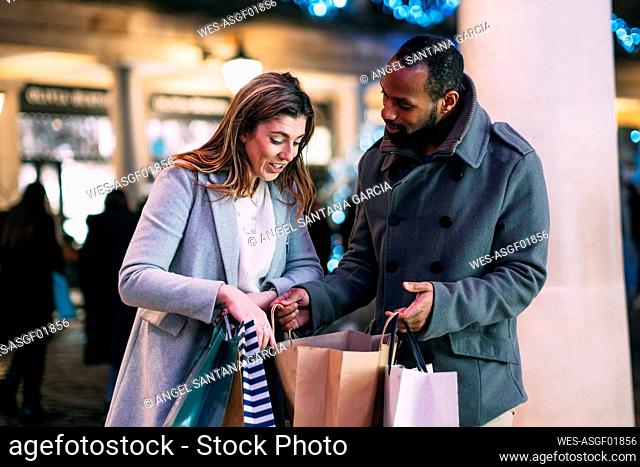 Woman discussing with man holding shopping bags at Christmas market