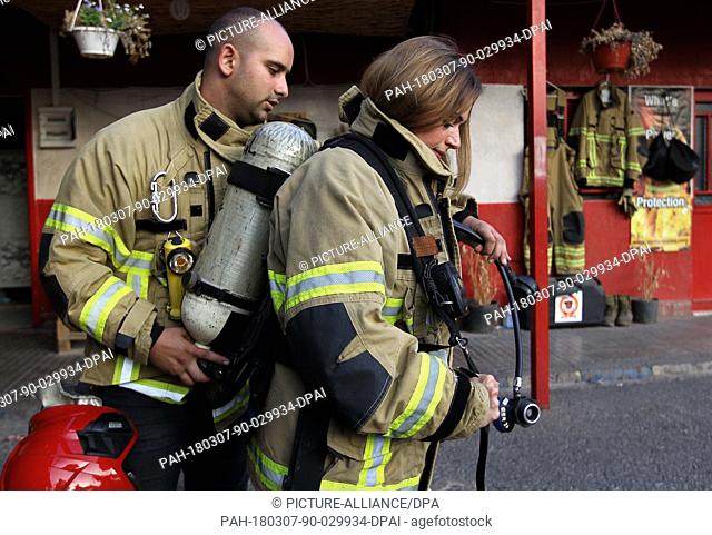A picture made available on 07 March 2018 shows a firefighter helping colleague Dalia Naamani (R), 40, to put on her oxygen tank during a drill at Lebanon's...