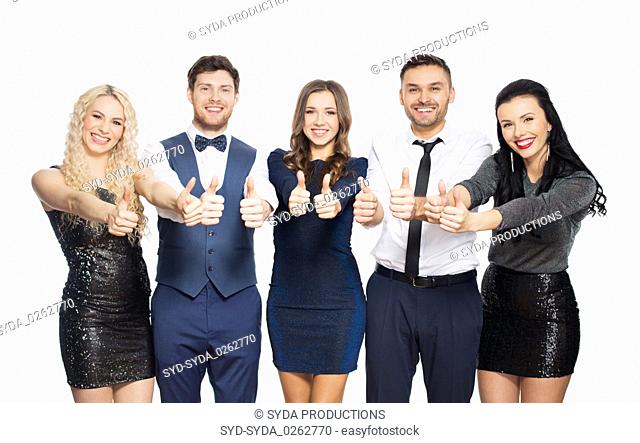 happy friends in party clothes showing thumbs up