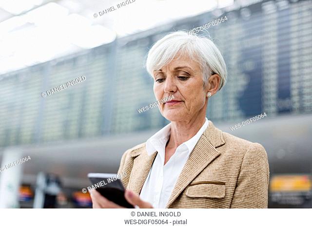 Senior businesswoman using cell phone at the airport