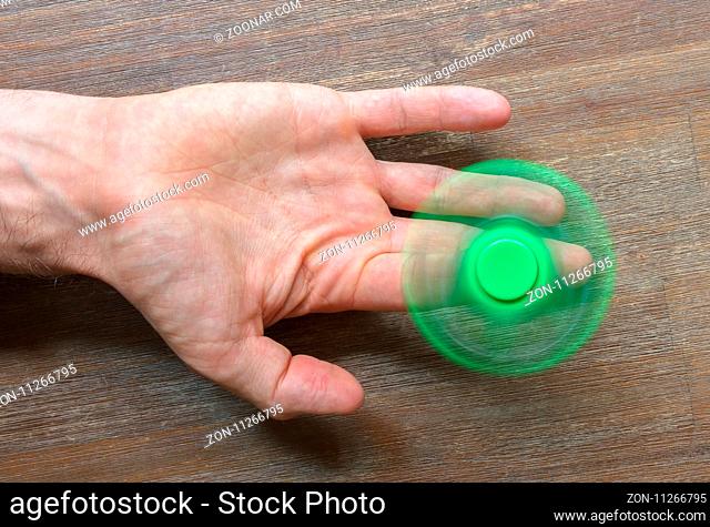 Image of Fidget finger spinner stress toy - Green spinner on a wooden desk