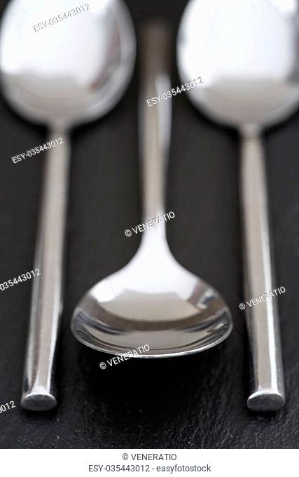 Macro image of modern cutlery spoons on rustic slate background