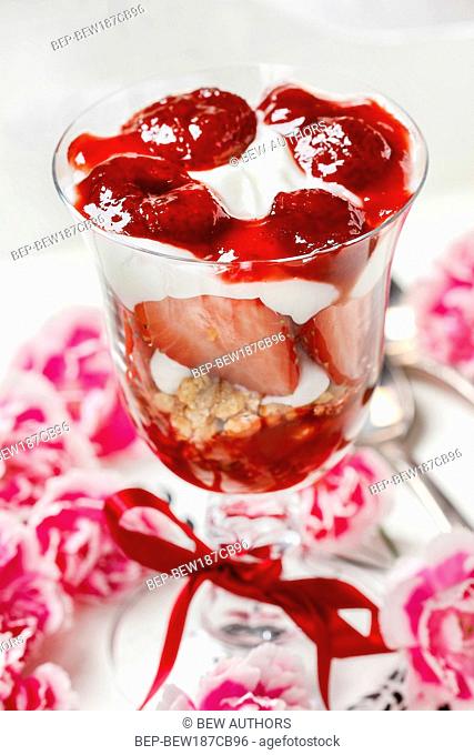 Layer strawberry and muesli dessert in glass goblet. Selective focus