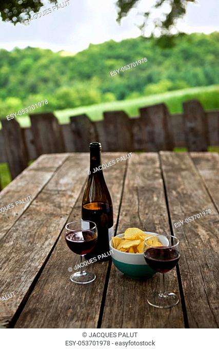 Tasting glass of red wine and chips on a terrace in the French countryside
