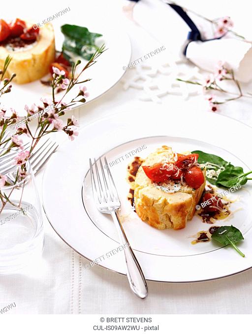 High angle view of goat cheese roulade with tomatoes and basil on elegant plate