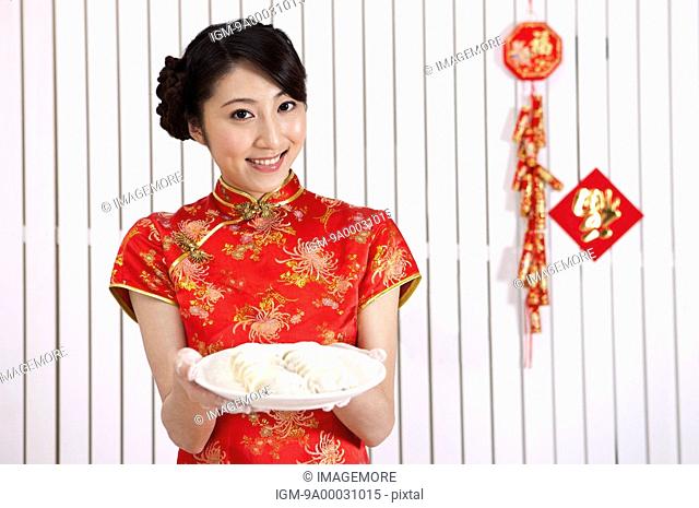 New Year, Young woman wearing Chinese traditional clothing and holding a plate of dumplings with smile