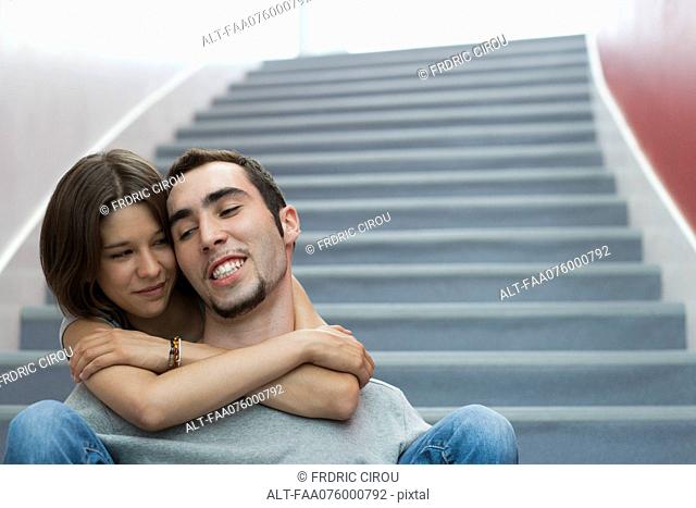 Young couple sitting on stairs, embracing