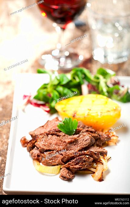 Scheiben vom Steak auf einen Teller mit Salat