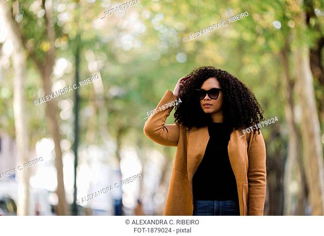 Stylish young woman in sunglasses walking in park