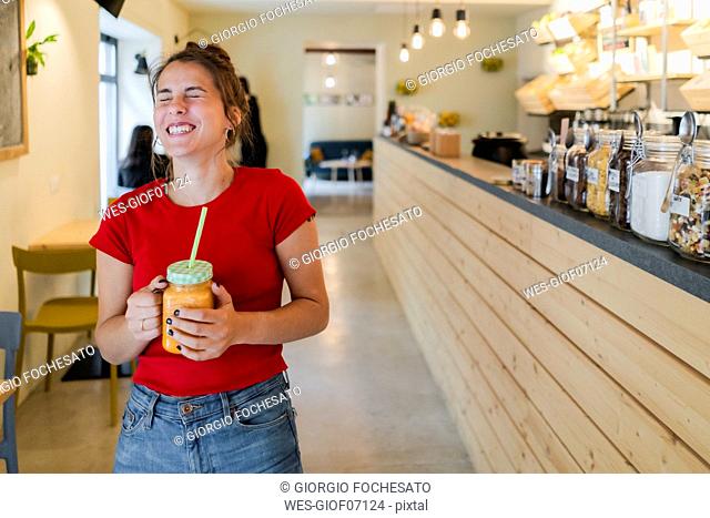 Happy young woman with a smoothie in a cafe