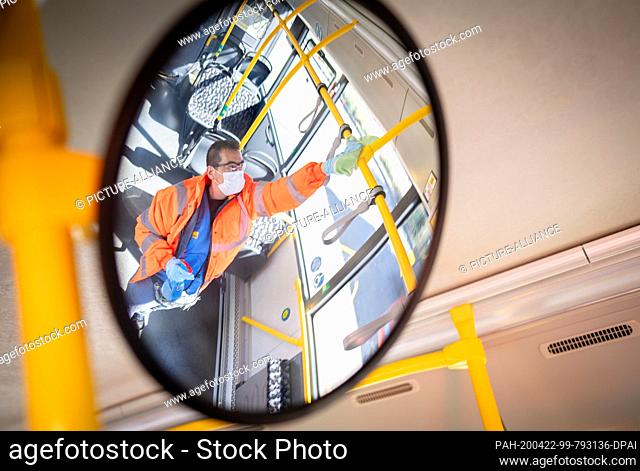 22 April 2020, Berlin: An employee can be seen in the mirror cleaning the passenger area of a BVG bus at the terminal stop Kurt-Schumacher-Platz