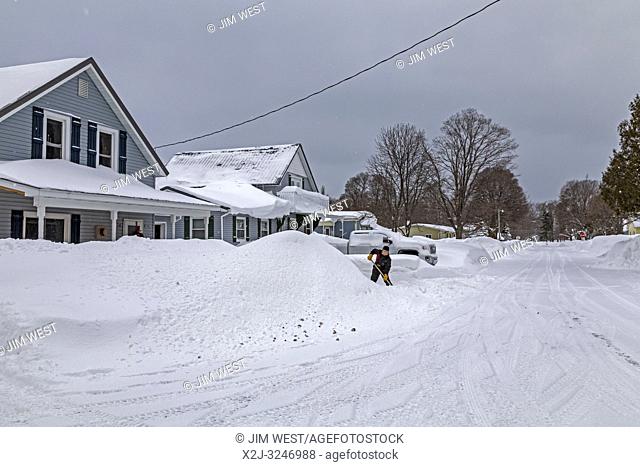 Grand Marais, Michigan - A woman shovels snow in front of a residence. The town, on the shore of Lake Superior, gets an average of 151 inches of snow per year