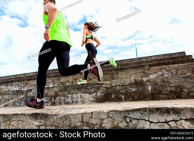 Sporty young couple in stylish sportswear running on stairs, photography for blog or ad of sport and healthy lifestyle. High quality photo