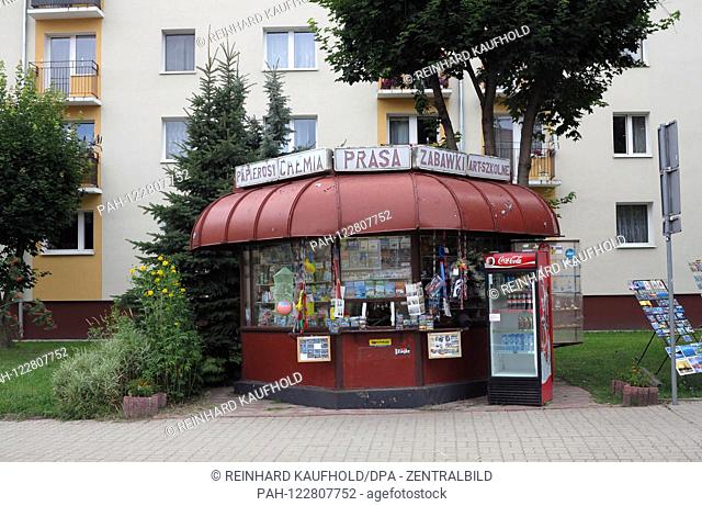 Small historical newspaper kiosk in the city of Gizycko (Loetzen) - in the background redeveloped prefabricated buildings from communist time, taken on 16