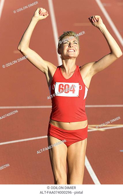 Woman running on track with arms raised in victory
