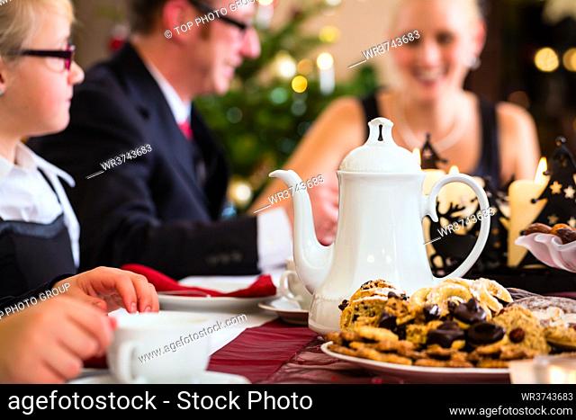 Parents and children celebrating Christmas with drinking coffee and X-mas cookies