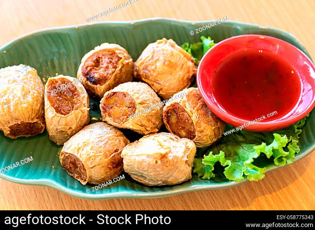 Hoi Jo, Deep Fried Crab Meat Rolls with sweet plum sauce. Thai street food and restaurant cuisine on wooden table