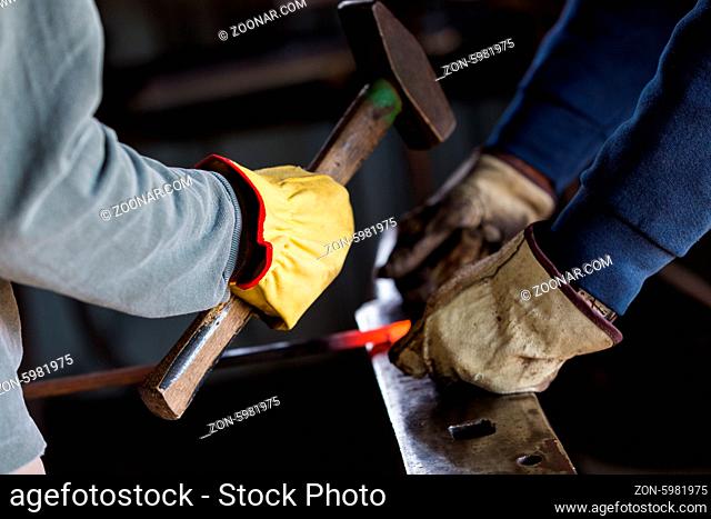 A blacksmith forging hot iron on the anvil