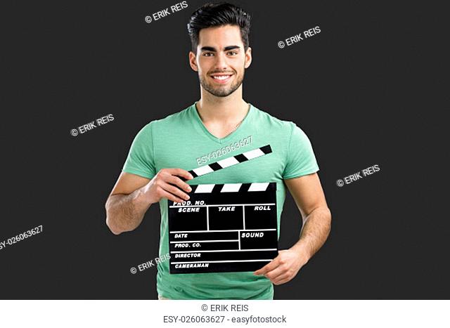 Portrait of handsome young man holding a clapboard, isolated on gray background