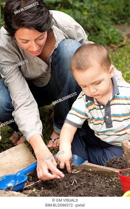 Hispanic mother gardening with son