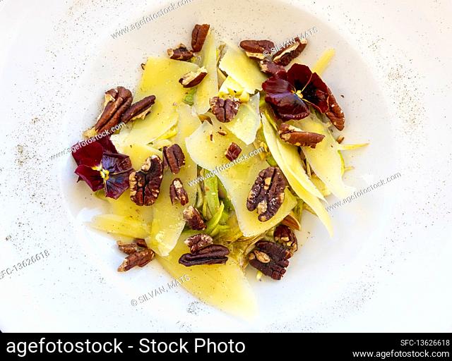 Lemon Scented Artichoke with Sbrinz Flakes Cheese and Roasted Nut Salad on a white Plate