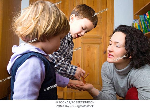 Mutter spielt mit ihren beiden Kindern im Kinderzimmer