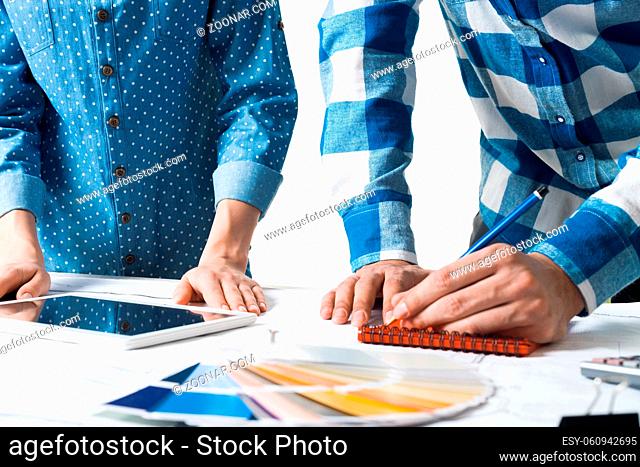 Designers working with color swatches and tablet computer at desk. Interior design, architectural decoration and renovation