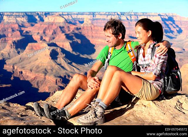 Hiking couple portrait - hikers in Grand Canyon enjoying view of nature landscape smiling happy. Young couple trekking, relaxing after hike on south rim of...