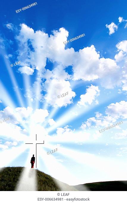 A person walking up to a glowing cross on a hill
