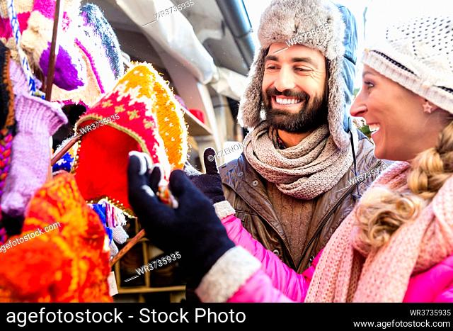 Couple buying winter clothes and hats on Christmas market