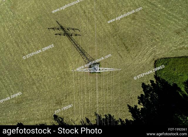 Aerial view electricity pylon over sunny green crop, Baden-Wuerttemberg, Germany